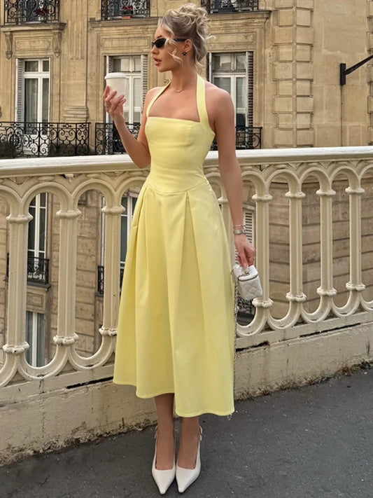 Woman in a yellow dress standing on a street with a building in the background