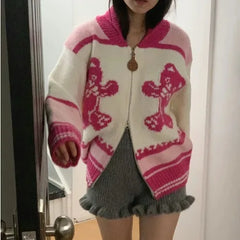 Person wearing a pink and white patterned cardigan in front of a mirror.