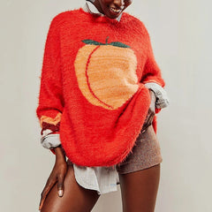 Person wearing a red sweater with a peach design on a plain background