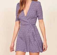 Woman wearing a purple floral dress on a beige background