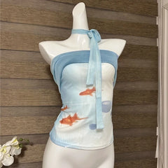 Mannequin wearing a blue and white bikini with fish design against a wooden panel background