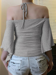 Person wearing a gray off-shoulder top and light denim shorts indoors.