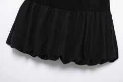 Women's black mini skirt with a balloon silhouette and gold buttons.