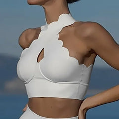 White scalloped bikini top worn by a person with a blurred background