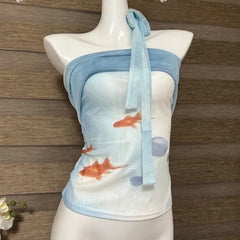 Mannequin wearing a blue strapless top with goldfish pattern against a wooden background