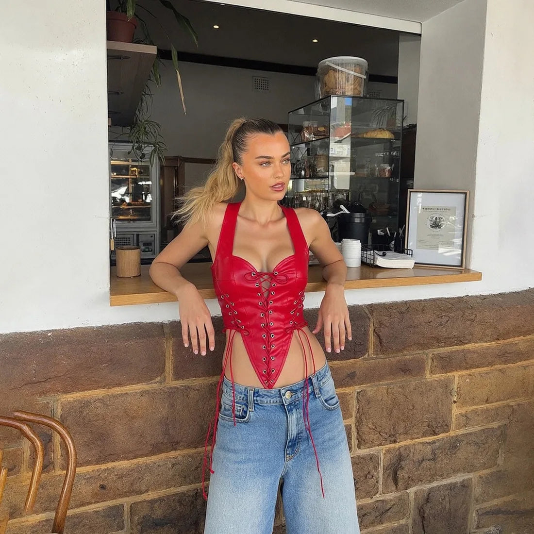 Woman in a red corset and blue jeans standing in front of a cafe counter.