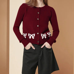Red cardigan with white bow patterns worn by a person 