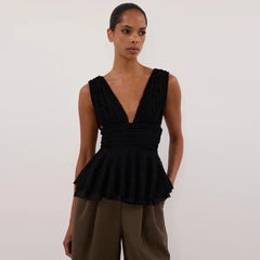 Woman wearing a black peplum top and brown pants 