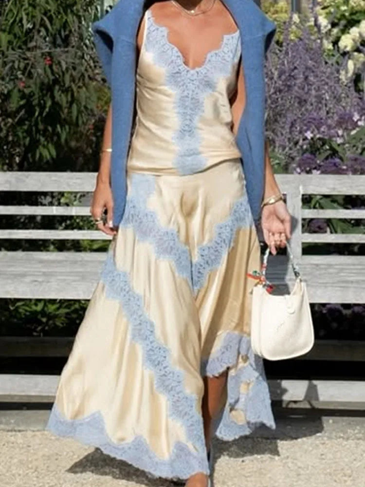 Woman wearing a beige dress with blue lace details and a matching cardigan, standing outdoors.