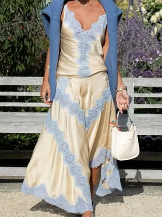 Woman wearing a beige dress with blue lace details and a matching cardigan, standing outdoors.