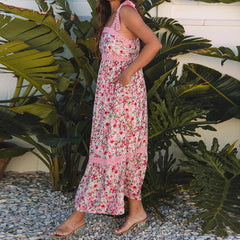 Woman in a floral dress standing among tropical plants- side view