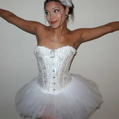 Person wearing a white ballet costume with arms outstretched against a plain background