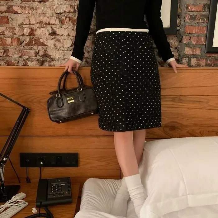 A woman wearing a stylish polka dot midi skirt, showing off its flattering fit and playful design.