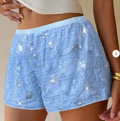 Light blue lace shorts with sequins worn by a person on a neutral background
