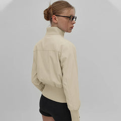 Person wearing a beige jacket and black shorts on a plain background