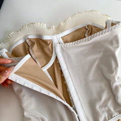 Close-up of beige lingerie with a hand holding it open on a light background