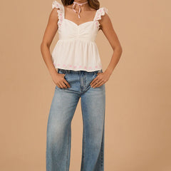 Woman wearing a white top with ruffled details and blue jeans