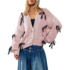 Pink knitted cardigan with black ribbons worn by a model 
