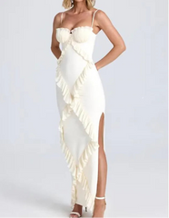 Woman wearing a white ruffled dress with a high slit on a light gray background