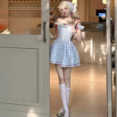 Person in a checkered dress standing in a room with wooden flooring and neutral walls.