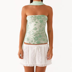 Woman wearing a light green floral top and white lace skirt 