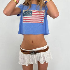 Person wearing a blue t-shirt with an American flag design and a white lace skirt.