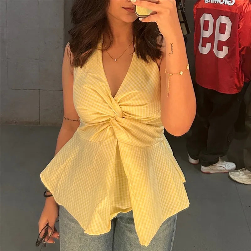 Close-up of a yellow gingham halter top featuring a prominent twist-front detail and a flared peplum hem.
