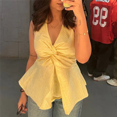 Close-up of a yellow gingham halter top featuring a prominent twist-front detail and a flared peplum hem.