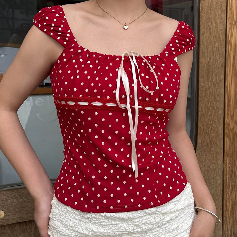 Red polka dot top with white skirt worn by a person, indoors.