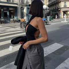 A woman wearing a black backless bodysuit with high-waisted jeans, showcasing its versatility and edgy style.