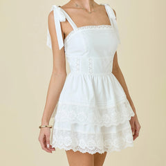 White lace dress with bow straps on a beige background