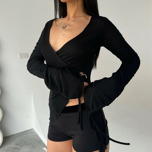 Person wearing a black long-sleeve top and shorts against a plain background
