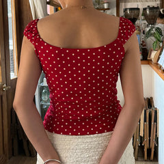 Person wearing a red polka dot top in an indoor setting