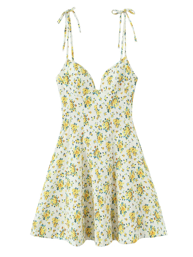 A sleeveless white A-line dress with a yellow and green floral print, featuring thin tie-shoulder straps and a sweetheart neckline, shown against a plain white background.