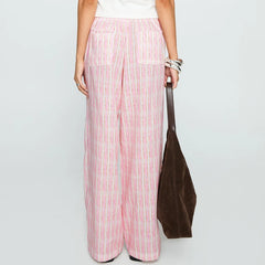 Person wearing pink striped pants holding a brown bag on a light gray background