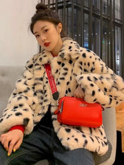 Person wearing a spotted fur coat with a red handbag indoors.