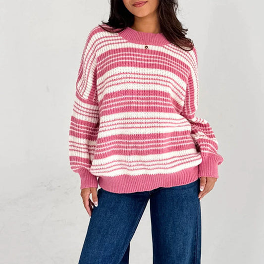 Person wearing a pink and white striped sweater with blue jeans on a light gray background