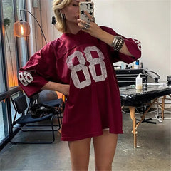 Person wearing a maroon oversized sweater with '88' design, taking a mirror selfie.