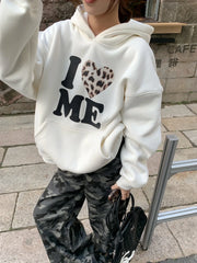Person wearing a white hoodie with 'I ❤️ ME' text and camouflage pants outdoors.