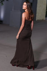 A woman wearing a black strapless dress with a flowing silhouette and unique cutouts, perfect for a special occasion.