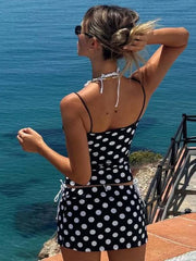 Woman in a black and white polka dot dress standing by the ocean