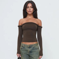 Woman wearing a brown off-shoulder top and jeans on a light gray background