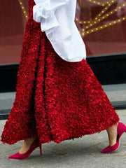 Person wearing a red textured skirt with a white top and pink shoes