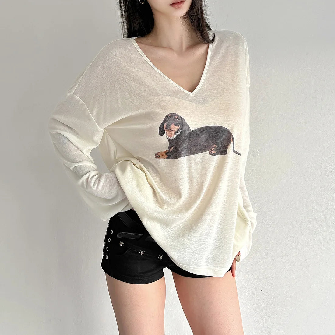 Person wearing a white long-sleeve shirt with a dachshund graphic 