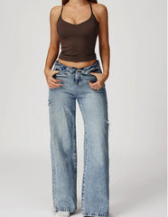 Person wearing a brown tank top and light blue jeans on a white background