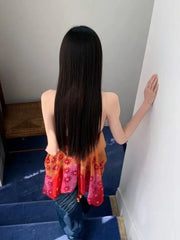 Person wearing a colorful top and blue jeans standing on a staircase.