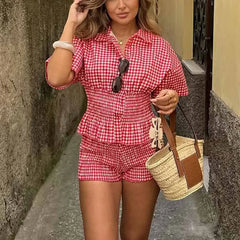 Woman wearing a red and white checkered outfit with a straw bag in an urban setting.