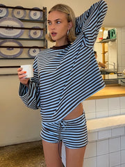 Woman in a striped outfit holding a mug in a kitchen setting