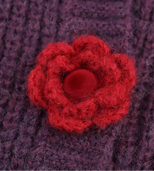 Red knitted flower on a purple textured fabric background