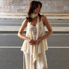Woman wearing a white lace top and pants standing on steps.